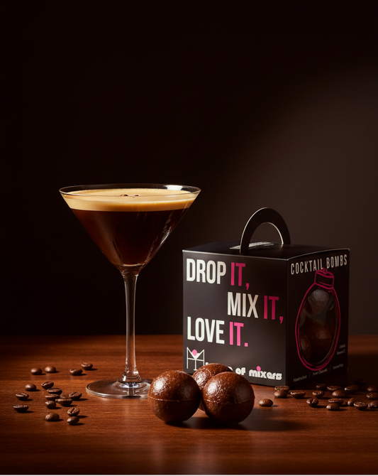 Cocktail in a martini glass with coffee beans on a wooden surface, featuring a box labeled 'Drop It. Mix It. Love It.'